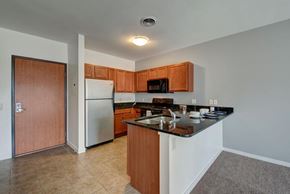 Milwaukee apartment for rent - A bright kitchen here at Latitude featuring warm wood cabinetry, black granite countertops, and stainless appliances, creating a clean, welcoming space with an open layout and functional breakfast bar.