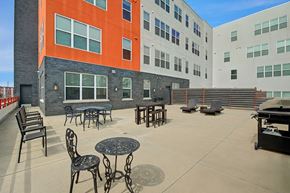 Milwaukee apartment for rent - A spacious outdoor patio here at Latitude featuring stylish seating areas, café tables, lounge chairs, and grilling space, creating a bright and inviting setting for relaxing and socializing.