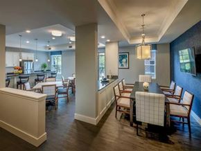 Shorewood apartment for rent - A community dining room here at Oaks of Shorewood featuring elegant tables, upholstered chairs, pendant lighting, and a bright, welcoming layout connected to a modern kitchen and lounge area.