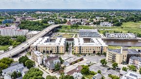 Milwaukee apartment for rent - A modern exterior building view of River House with large windows, a neutral-toned exterior, and a welcoming entrance. The property creates a stylish multi-story design and create an attractive, upscale atmosphere.