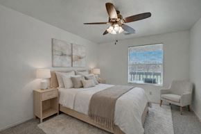 Milwaukee apartment for rent - A bright bedroom here at St. James Place with soft beige carpet, cream walls, and a large window that brings in natural light. A ceiling fan and cozy layout create a comfortable and inviting atmosphere.