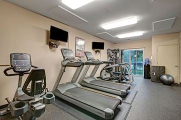 Fitchburg apartment for rent - A gym with treadmills, elliptical machines, and a television.