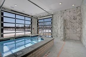 Fitchburg apartment for rent - A modern indoor spa here at The Lafayette with a relaxing hot tub, marble tile walls, and glass garage-style doors. A walk-in shower and bright natural light create a refreshing, upscale wellness space.