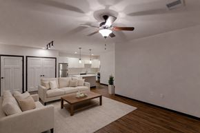Deforest apartment for rent - A bright living room here at The Park featuring a beige sofa and matching armchair, wooden coffee table on a soft rug, and open kitchen with white cabinets, creating a warm, modern, and welcoming space.