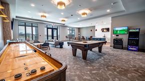 Sun Prairie apartment for rent - A spacious resident lounge here at Van Buren East with a pool table and shuffleboard. A community kitchen, arcade games, and comfortable seating create a fun, social, and inviting atmosphere.