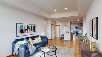 Sun Prairie apartment for rent - A living room with a blue couch and a painting on the wall.