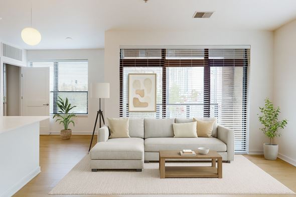Milwaukee apartment for rent - A bright living room here at Vim and Vigor with a light sectional sofa, large windows with blinds, warm wood flooring, a neutral rug, and modern décor creating an open, airy, and welcoming space.
