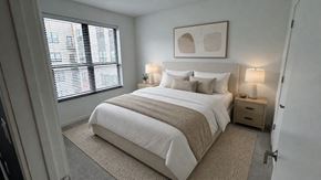 Milwaukee apartment for rent - A bedroom with a large bed and a window with blinds.