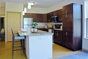 Fitchburg apartment for rent - A kitchen here at Vue at Pinnacle Park with brown cabinets and a white island.