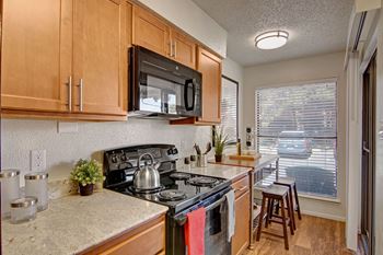 A kitchen with light cabinets and black appliances