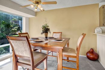 An in-unit dining area next to the kitchen with table, chairs, and ceiling fan