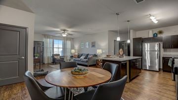 Sun Prairie apartment for rent - A modern open-concept kitchen, dining, and living room with a wooden dining table and chairs.
