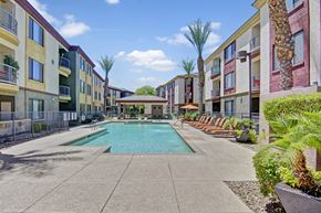 Peoria apartment for rent - A pool surrounded by palm trees and apartment buildings.