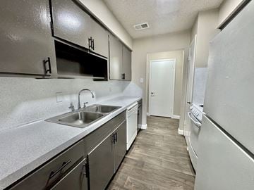 Corpus Christi apartment for rent - A kitchen with a white fridge, stainless steel sink and cabinets.
