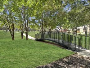San Antonio apartment for rent - A black metal fence borders a grassy area with trees.