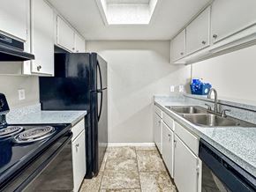Corpus Christi apartment for rent - Modern kitchen with black appliances and white cabinets at Towne Oaks Apartments.