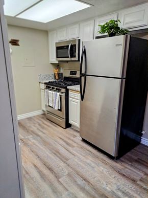 Highland apartment for rent - A black refrigerator stands in a kitchen with a stove and microwave in the background at Raintree Apartments, CA 92346