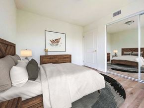 San Bernardino apartment for rent - A bedroom with a large bed and a mirror on the wall.