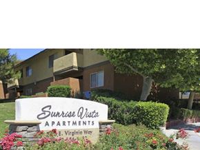 Barstow apartment for rent - A sign for Sunrise Vista Apartments is in front of a building.