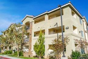San Bernardino apartment for rent - A beige building with a red brick pillar in front of it.