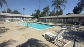 Redlands apartment for rent - A pool with a sun lounger in front of a building.