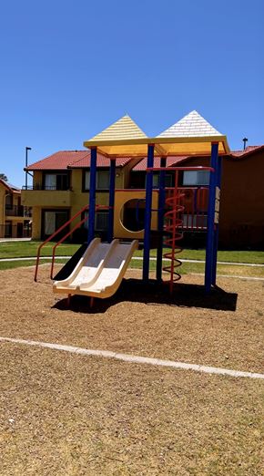 Barstow apartment for rent - A playground with a yellow slide and a red and blue structure.