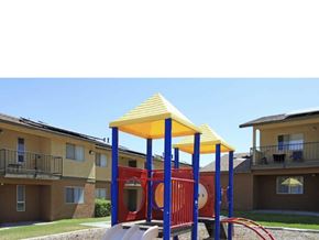 Barstow apartment for rent - A playground with a yellow canopy and red and blue structure in front of apartment buildings.