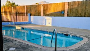 Yucaipa apartment for rent - A small pool with a diving board and a metal fence.