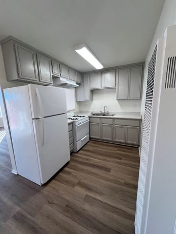 Ontario apartment for rent - A white refrigerator is in a kitchen with wooden floors.