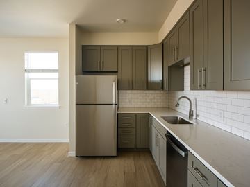 Longmont apartment for rent - A kitchen with a stainless steel refrigerator and dark wood cabinets.