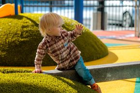 Longmont apartment for rent - A young child in a plaid shirt and blue jeans is playing on a playground.