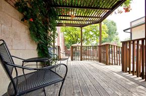 Longmont apartment for rent - A black metal bench sits on a wooden deck under a pergola.