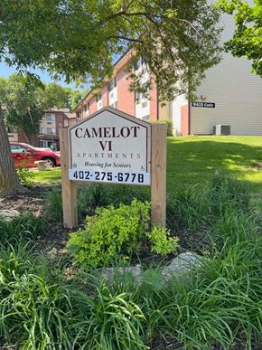 Omaha apartment for rent - A sign for Camelot Apartments is in front of a building.