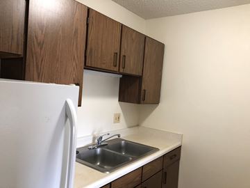Cedar Rapids apartment for rent - A kitchen with a white fridge and brown cabinets.