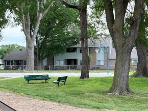 Council Bluffs apartment for rent - a park bench sitting in the grass near some trees
