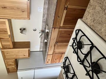 Council Bluffs apartment for rent - A kitchen with a stove top oven and wooden cabinets.