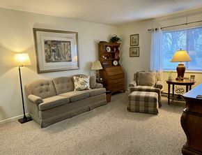 Centralia apartment for rent - A living room with a grey sofa, a wooden cabinet, a chair, a table, and a lamp.