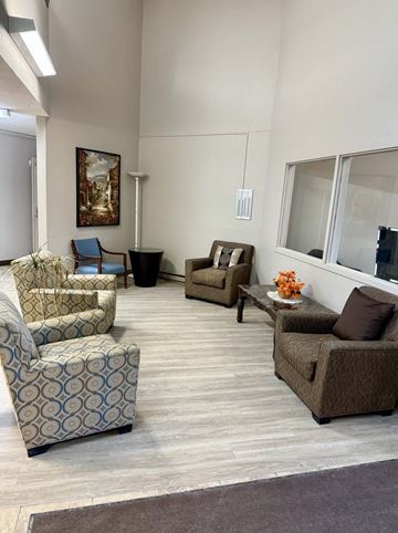 Omaha apartment for rent - A living room with a painting on the wall and a sofa with a pillow on it.