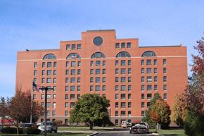 Taylorville apartment for rent - a large brick building with many windows and an american flag in front of it