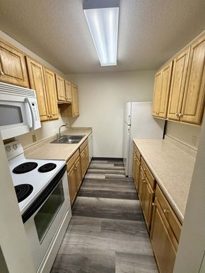 Omaha apartment for rent - A kitchen with wooden cabinets and a white stove top oven.