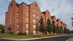 Naperville apartment for rent - A long brick building with trees in front.