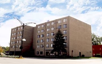 Urbana apartment for rent - A large tan building with a tree in front of it.