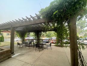 Marion apartment for rent - A wooden pergola with green vines growing on it is situated over a patio table.