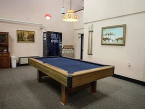 Wahoo apartment for rent - A pool table in a room with a cabinet and a painting on the wall.