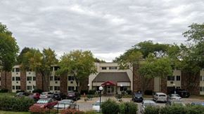 Harlan apartment for rent - A parking lot with cars and a building in the background.