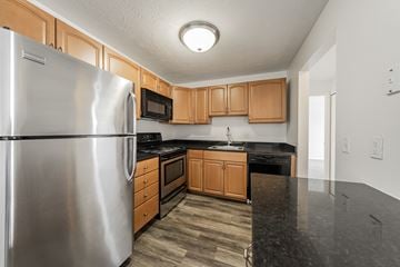 Chardon apartment for rent - A kitchen with a stainless steel refrigerator and wooden cabinets.