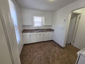 Mentor house for rent - A kitchen with white cabinets and a brown floor.