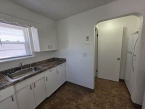 Mentor house for rent - A kitchen with white cabinets and a marble countertop.