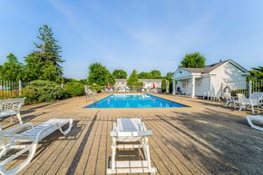 Olmsted Falls apartment for rent - A pool surrounded by white chairs and a wooden deck.
