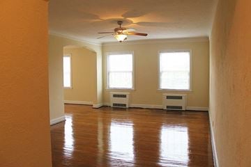 Cleveland Heights apartment for rent - an empty living room with a ceiling fan and three windows
